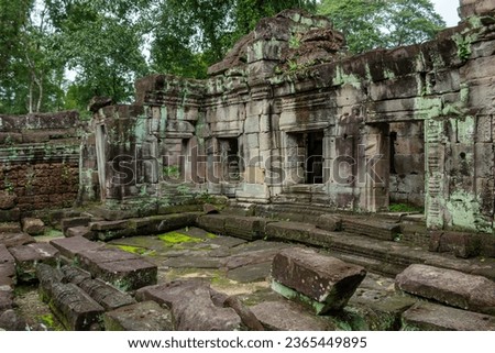 Moss covered green stone temple exterior and bricks at the Ta Prohm Tomb Raider Temple complex structure wall in Angkor Wat historical site, Seim Reap, Cambodia Royalty-Free Stock Photo #2365449895