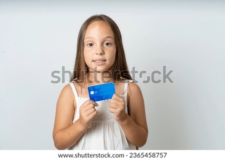 Photo of Young beautiful kid girl wearing white dress positive smile hold credit card income salary