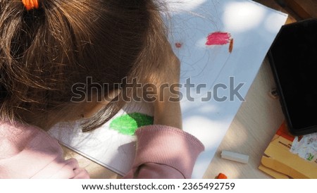 Child girl painting a picture with school supplies, preschool child painting, child drawing by colour pencils, child doing homework. children's creativity, early development, fine motor skills.
