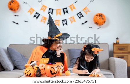 Family mother and daughter prepare decorations for Halloween at home. Draw pictures and cut paper together. and participate in creativity