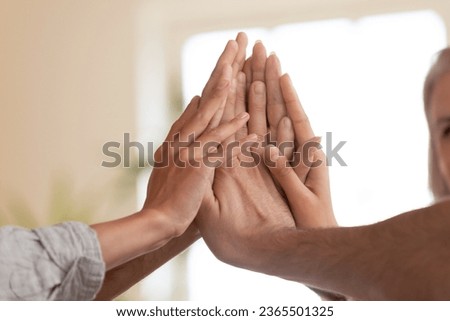 Close up european people palms stacked together, symbol of greet high 5 five gesture. Touch hands of each other sign of celebration great result sales growth, business leadership, teambuilding concept