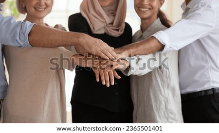 Middle-aged 50s and millennial businesspeople associates smiling standing in row stacked palms together showing unity and amity close up, team building, gender and racial equality cooperation concept Royalty-Free Stock Photo #2365501401