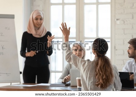 Middle eastern ethnicity woman coach in hijab and seminar participant interaction at group educative meeting in office, employee staff member raise hand ask question, having opinion, solution concept Royalty-Free Stock Photo #2365501429