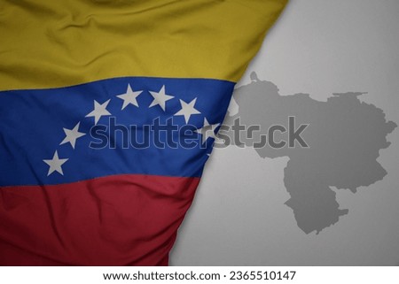 big waving national colorful flag and map of venezuela on the gray background. macro