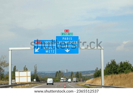 large road sign on the road leading to Paris or Luxembourg and some car traffic