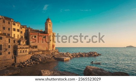 Tellaro village at sunset. The church and a small boat in the sea. Golfo dei Poeti or Gulf of Poets. Liguria region, Italy, Europe.