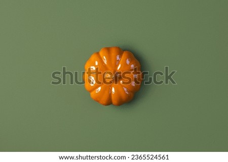Halloween background with orange pumpkin. Modern Holiday design. Halloween party border on olive green natural colour backdrop. Flat lay, top view, copy space. Thanksgiving trendy fall decoration 2023