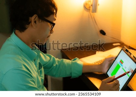 The image of a young man using an iPad to work on a table.