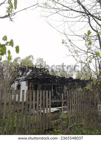 The ruins of a wooden house in the countryside after a fire. Spring, inclement weather, sad picture.