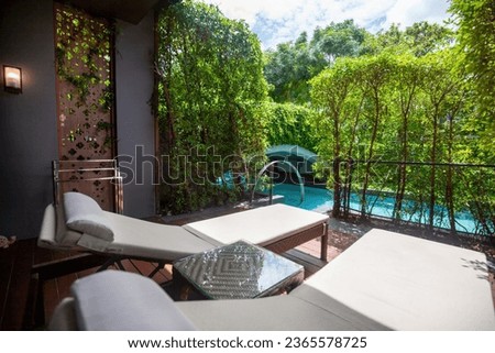 Wooden deck with two lounge chairs, overlooking the pool. Outdoor furniture, patio design, relaxation, vacation.