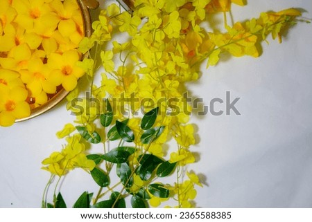 Brass colored round vessel containing water with flowers in it and an antique box near it ,space of text, yellow petals floating on a vessel, traditional vessel with water and flowers, yellow trumpet,