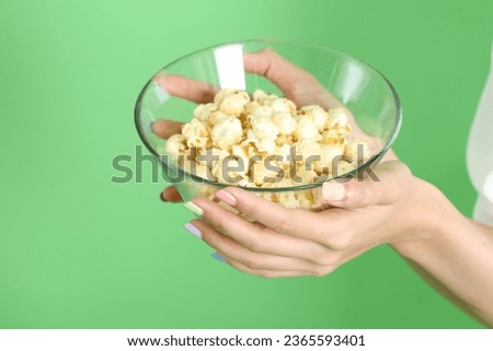 The Asian woman holding popcorn in the hand on the yellow background.