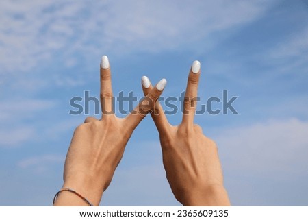 two hans of a girl forms the letter W on blue sky Royalty-Free Stock Photo #2365609135