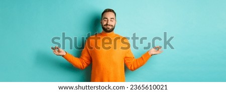 Image of relaxed and relieved man close eyes and smiling, feeling stress-free, meditating with calm expression, standing over light blue background. Royalty-Free Stock Photo #2365610021