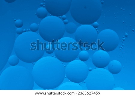 Macro photo with circles oil droplets water surface. Abstract blue background with oil bubbles