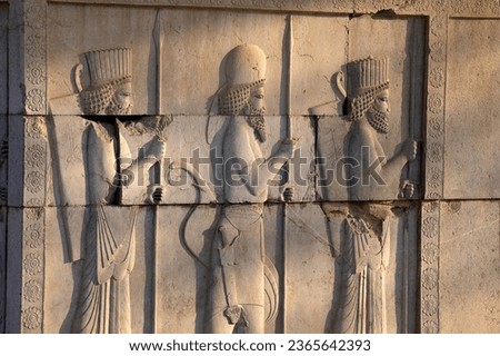 Image of ancient Persian ambassadors. Bearded men facing each other and holding hands. An ancient relief on the walls of the ruined Persepolis city.Iran. Royalty-Free Stock Photo #2365642393