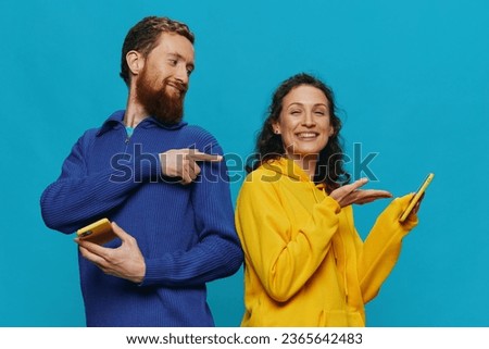 Woman and man cheerful couple with phones in their hands crooked smile cheerful, on blue background. The concept of real family relationships, talking on the phone, work online.