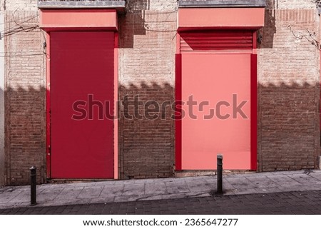 Facade of a reddish colored commercial premises on a street with bollards Royalty-Free Stock Photo #2365647277