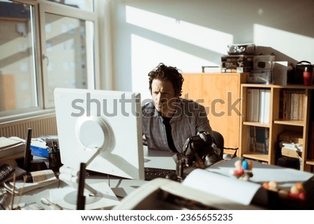 Young Caucasian male photographer going over his work on the computer in a media company office
