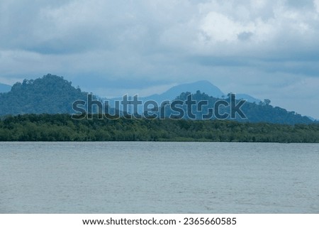 a view of beach, mountains and hills under cloudy sky