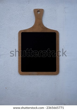 Wooden cutting board on white concrete wall. Vertical photo. Black chalk board. Copy space for text. Concept for street cafe menu, catering, offer, cafe, pub, bar, food, restaurant, cooking. Copyspace