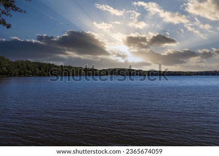 a stunning shot of the vast still blue lake water with lush green trees along the banks of the lake with powerful clouds at sunset at Lake Peachtree in Peachtree City Georgia USA	