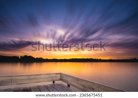 Panoramic Tranquil golden hour cloud above the forest lake at sunset. Dramatic cloudscape. Long exposure on the water, natural mirror. water ripple sunset background.