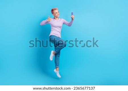 Full size body photo of young promoter blogging lady jumping thumb up recommend new event for followers selfie isolated on blue background