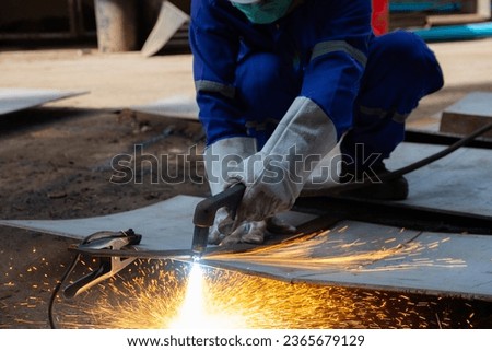 Worker cutting steel plate with Plasma Cutting process. Plasma cutting is a process that cuts through electrically conductive materials by means of an accelerated jet of hot plasma. Royalty-Free Stock Photo #2365679129