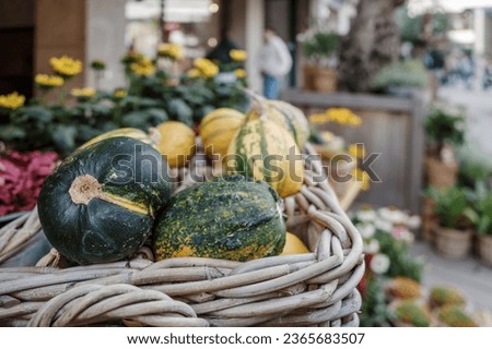 Selective focus at heap of pumpkins in weave basket as halloween decorative props outside store on the sidewalk. 
