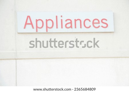 appliances word writing caption text sign in red on white rectangle background on beige building wall exterior outside outdoors, top of frame