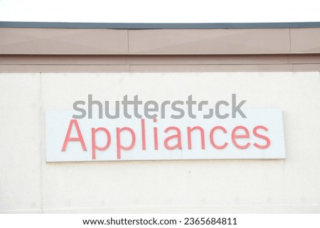 appliances word writing caption text sign in red on white rectangle background on beige building wall exterior outside outdoors, middle of frame