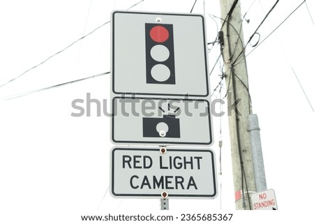 red light camera text sign with three atop each other with illustration of picture camera and red traffic light on metal post