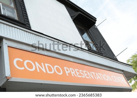 condo presentation centre center horizontal rectangle red white silver sign on store storefront with windows above outside in summer