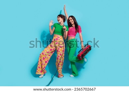 Full body photo of atmosphere karaoke party two singing vocalists girlfriends mic holding music player isolated on blue color background
