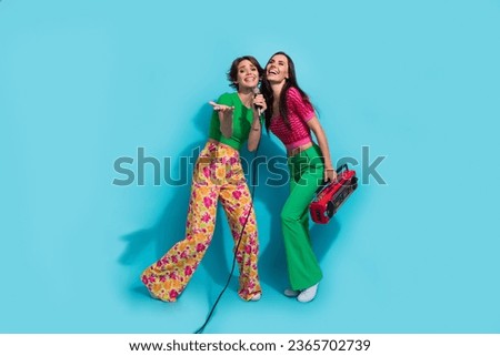 Full body photo of two vocalists young girls singer karaoke party vintage cassette recorder invite you isolated on blue color background