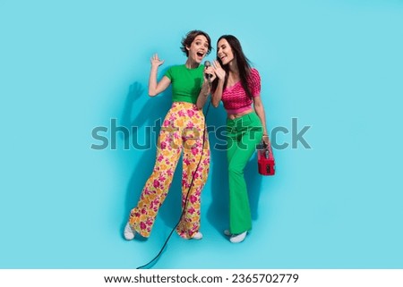Full size body photo of two singing drunk girlfriends weekend karaoke discotheque hold boombox player isolated on blue color background