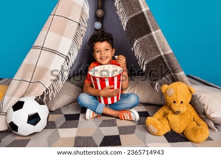 Photo of cute sweet kid boy enjoy free time watch series with pop corn isolated blue color background
