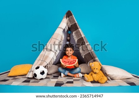 Photo ofcute boy have party eating water melon in handmade tent isolated blue color background