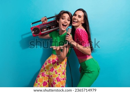 Photo of impressed sweet ladies wear colorful clothes listening boom box music singing karaoke isolated blue color background