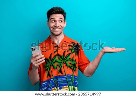 Photo of satisfied young tourism lover guy hold palm demonstrate website for buy tickets discount phone isolated on blue color background