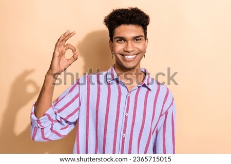 Photo portrait of handsome young male showing okey symbol quality wear trendy striped formalwear outfit isolated on beige color background