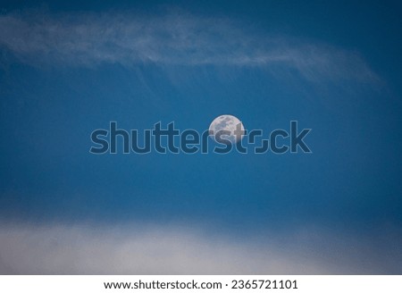 Horizontal Image of the moon in the daylight sky  with high cirrus clouds