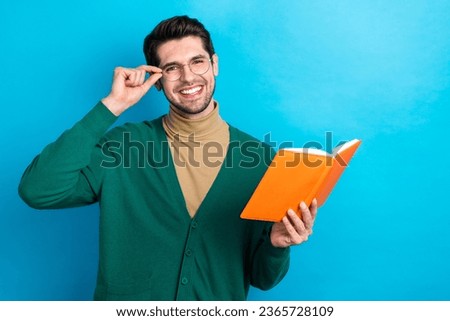 Photo of young man brunet wear green cardigan touch his glasses holding red diary copybook intellectual isolated on blue color background