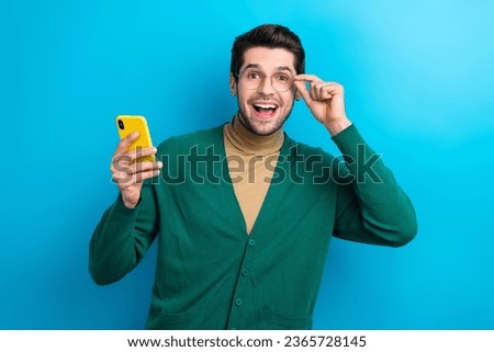 Photo of cool excited man wear green cardigan arm spectacles reading sms modern device isolated blue color background