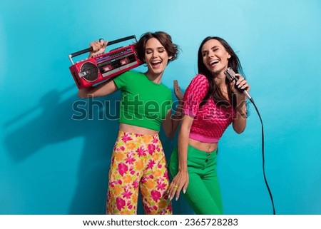 Photo of excited sweet ladies wear colorful clothes enjoying boom box songs singing mic isolated blue color background