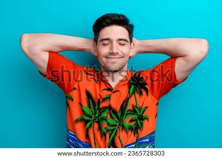 Photo of handsome man with stylish hairdo dressed print shirt arms behind head eyes closed sleeping isolated on blue color background