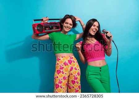 Photo of dreamy excited ladies wear colorful clothes listening boom box music singing karaoke isolated blue color background