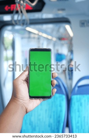 young man hand using smart phone with green screen inside of metro train