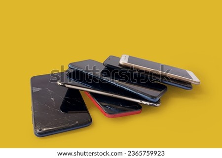 Smartphones with scratched tempered glass isolated on yellow background